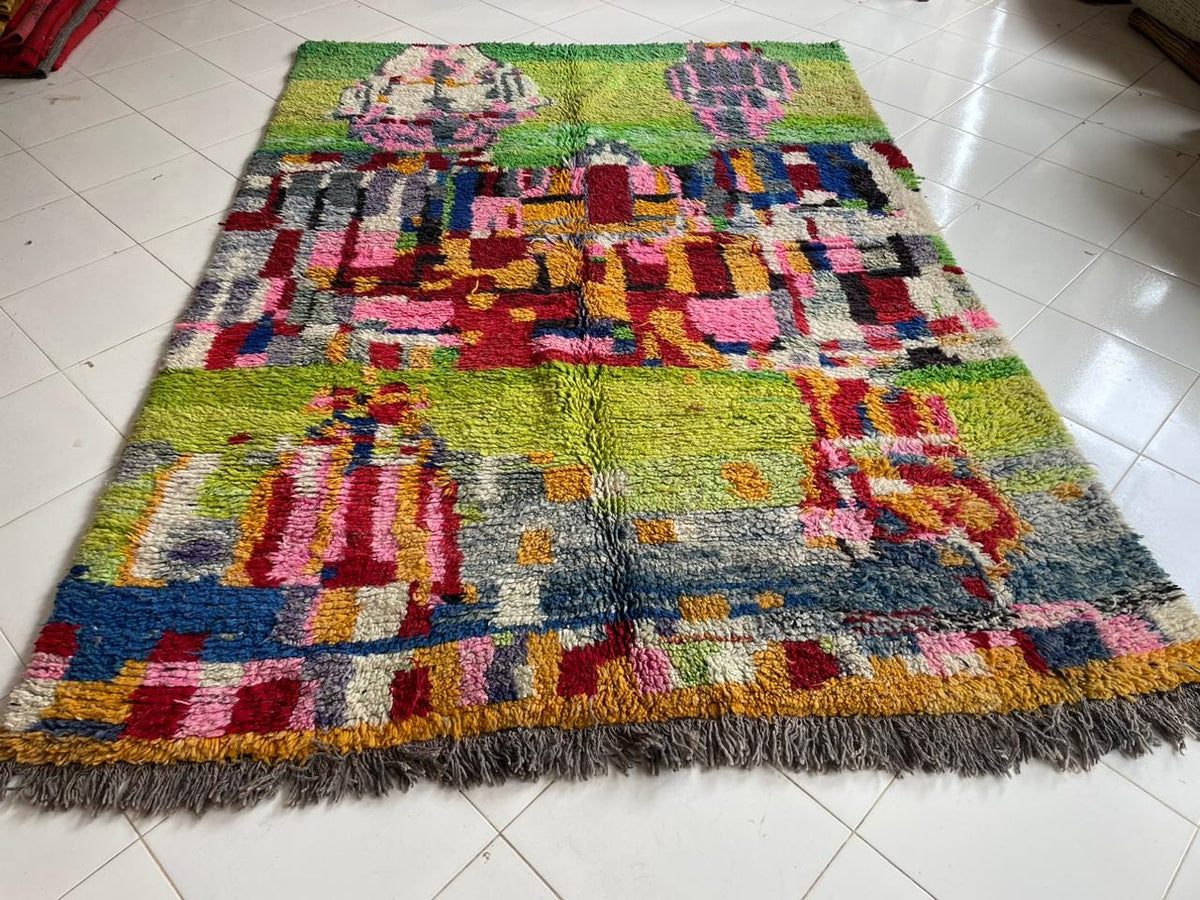 Close-up detail of a colorful Moroccan rug with fringed edges and abstract patterns.
