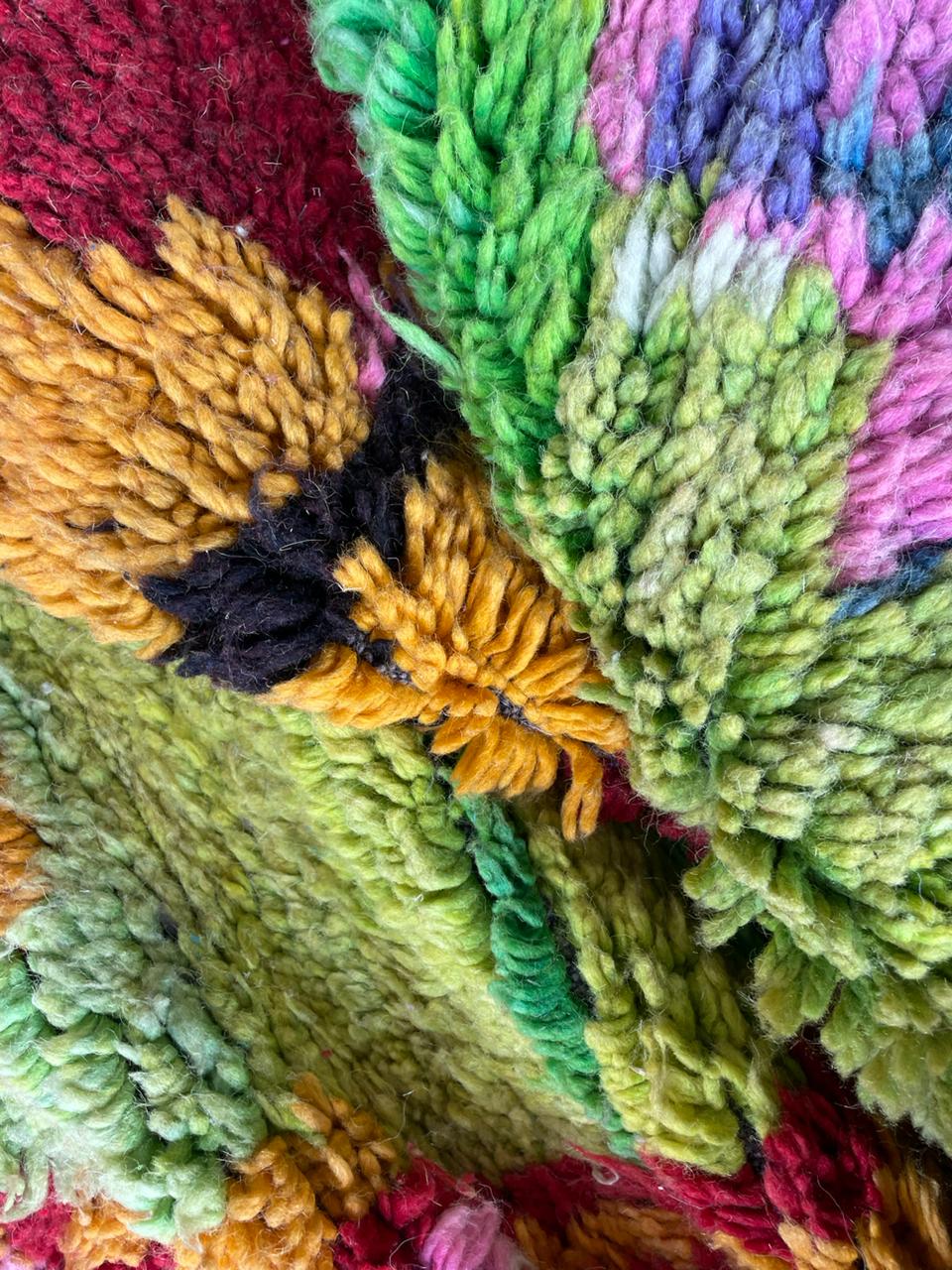 Close-up detail of a colorful rug with textured fibers and vibrant patterns.