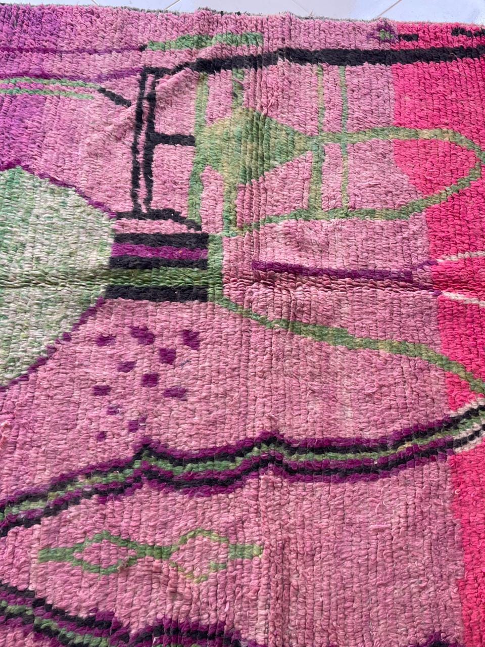 Detail shot of a pink Moroccan rug featuring geometric patterns and a textured fabric.