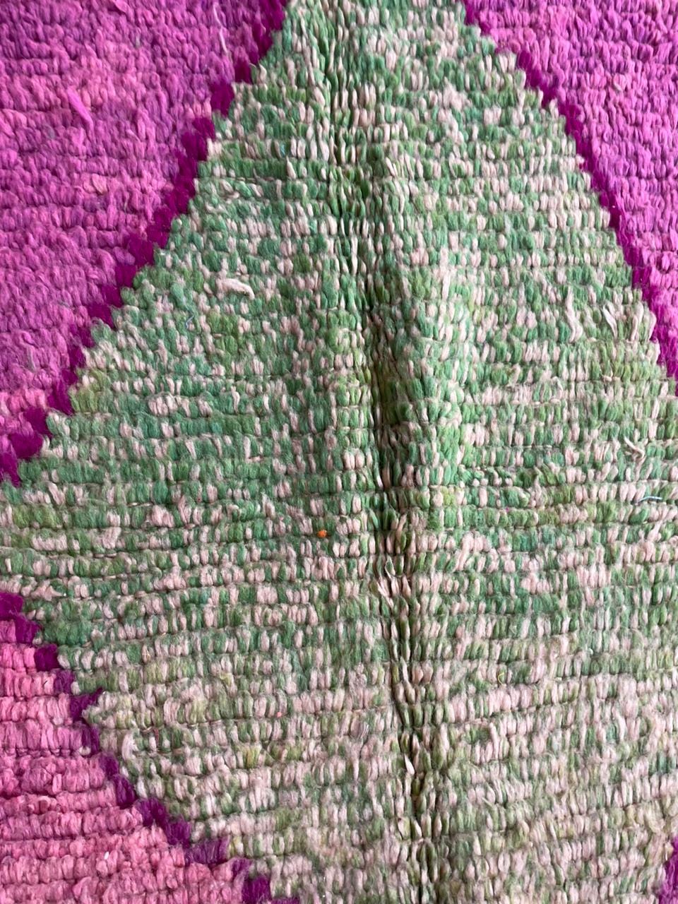 Close-up of a pink Moroccan rug with a leaf design and woven texture.