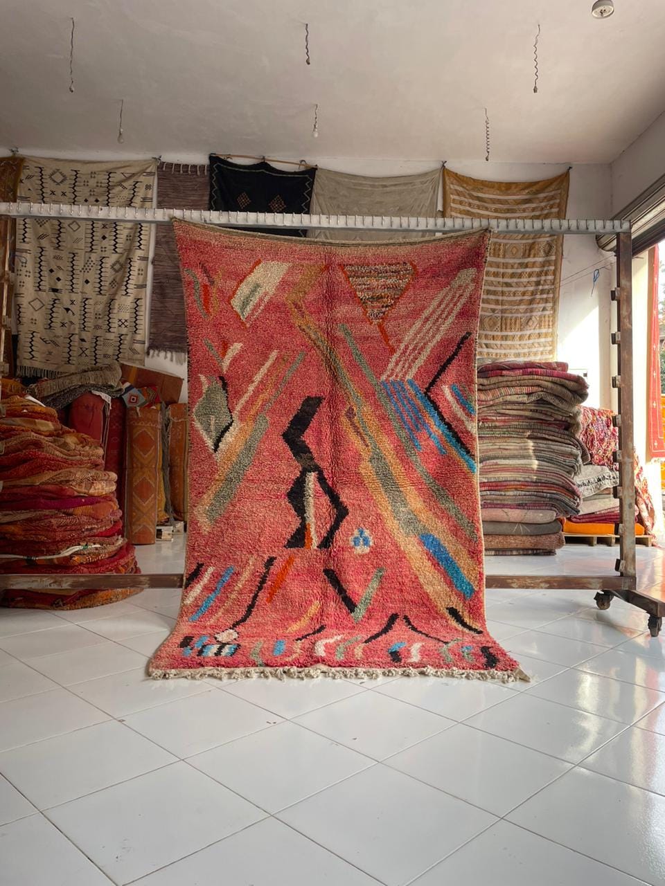 Lifestyle shot of a pink vintage Moroccan rug with geometric patterns and fringe edges.