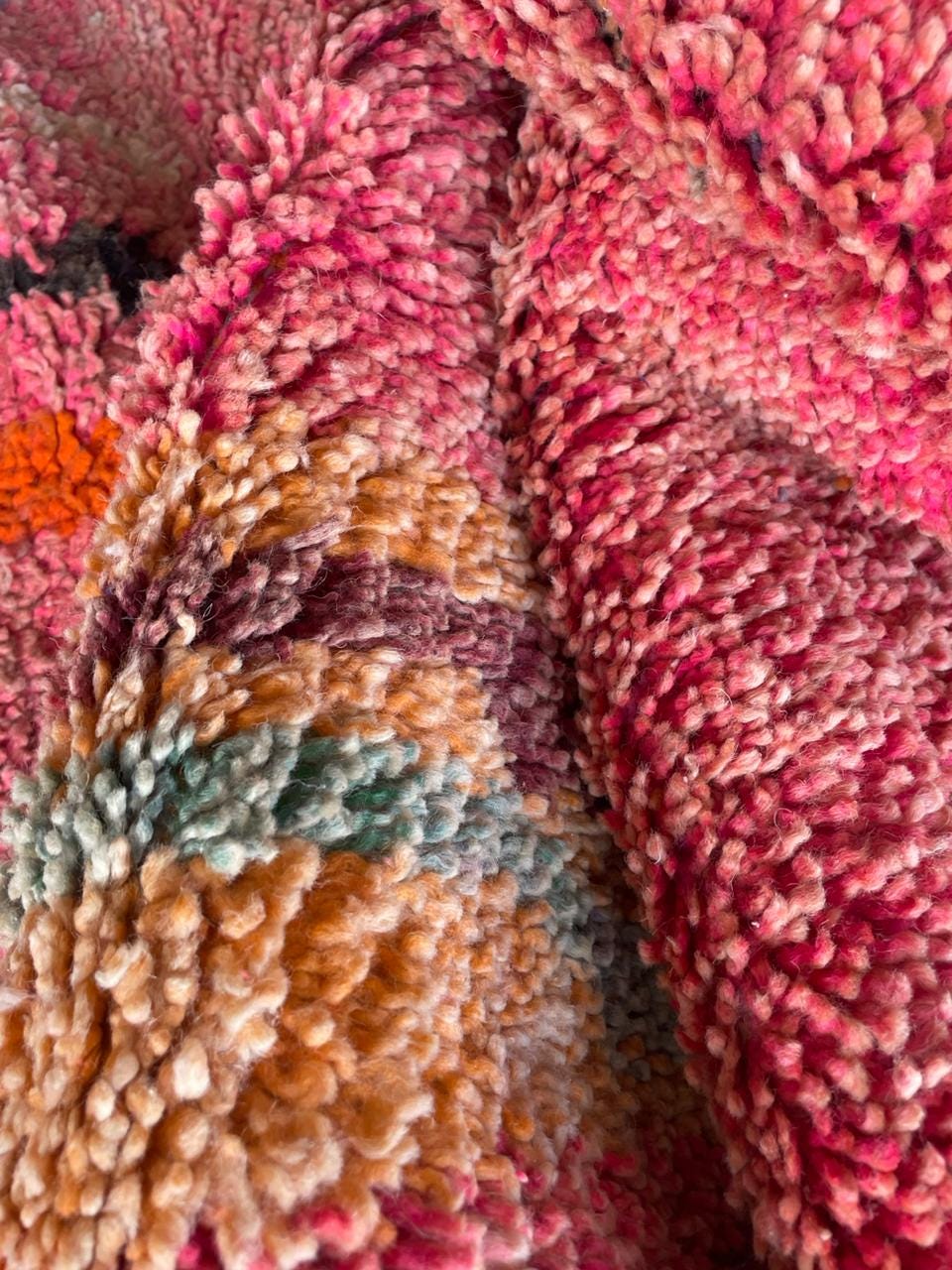 Close-up detail of a pink Moroccan rug featuring a textured surface and colorful design.
