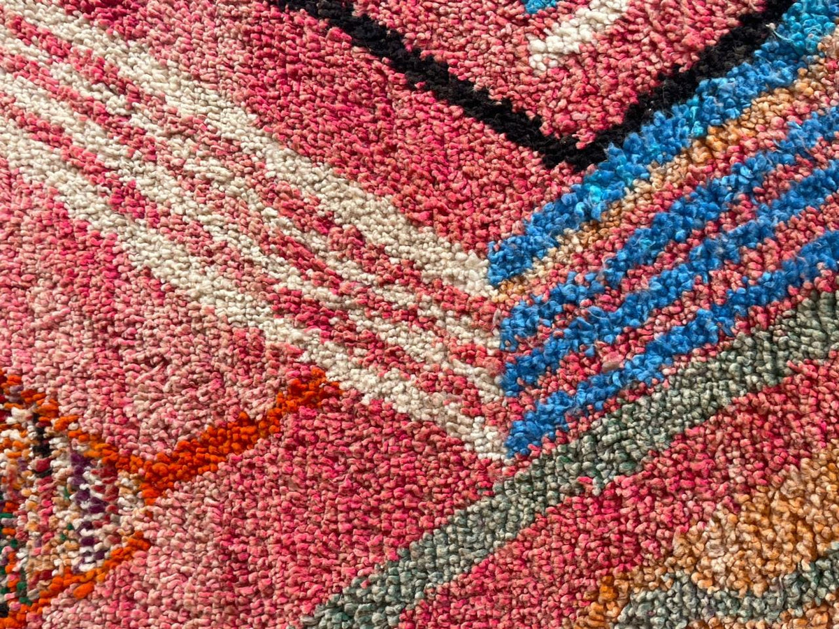 Close-up detail of a pink vintage Moroccan rug highlighting geometric patterns and textured surface.