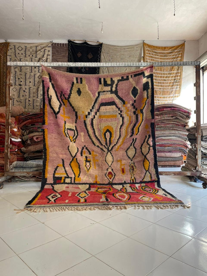 Lifestyle shot of the pink vintage Moroccan rug showcasing geometric patterns and fringe edges.
