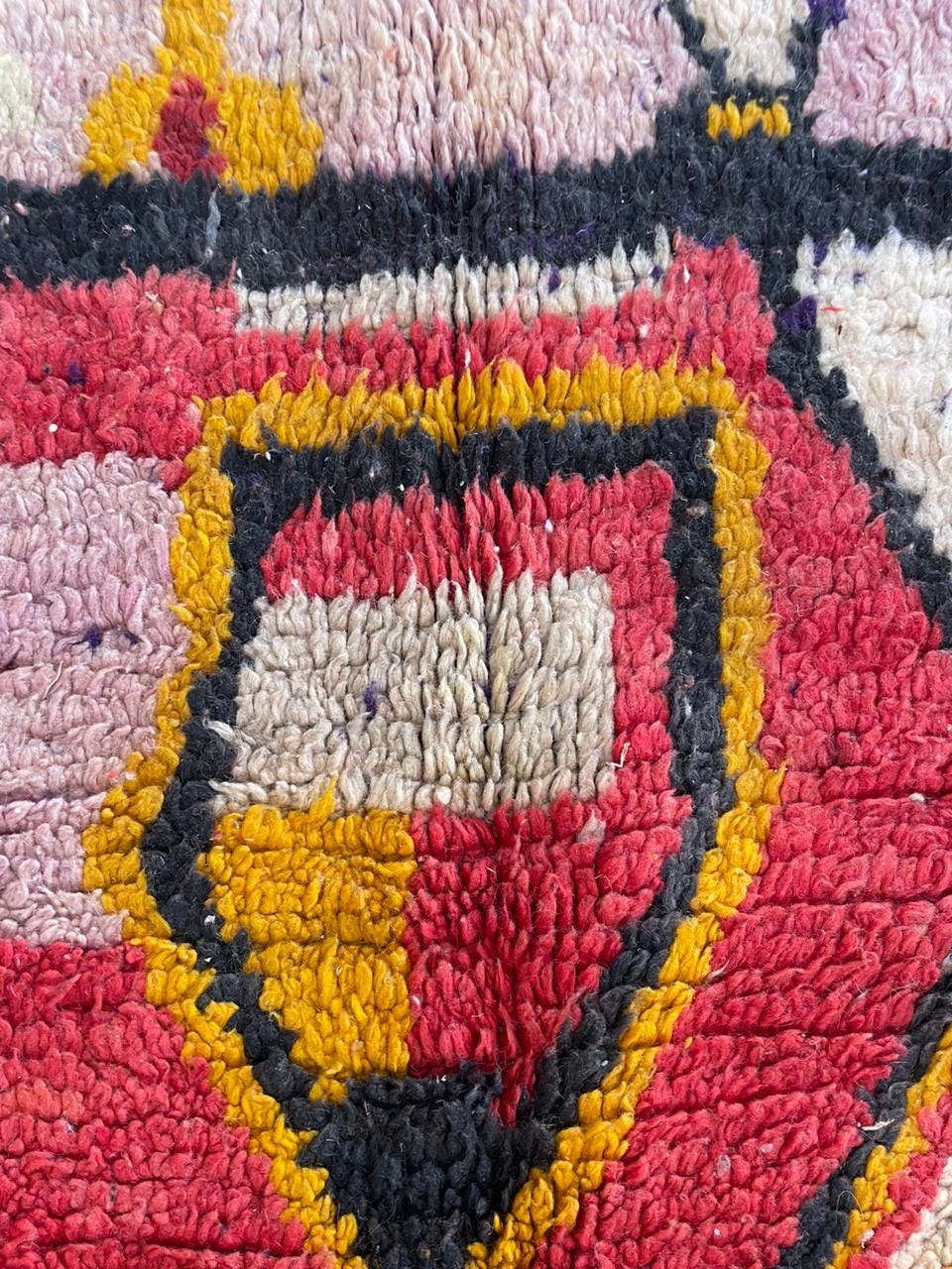 Detail view of the colorful Moroccan rug displaying geometric patterns and a textured surface.