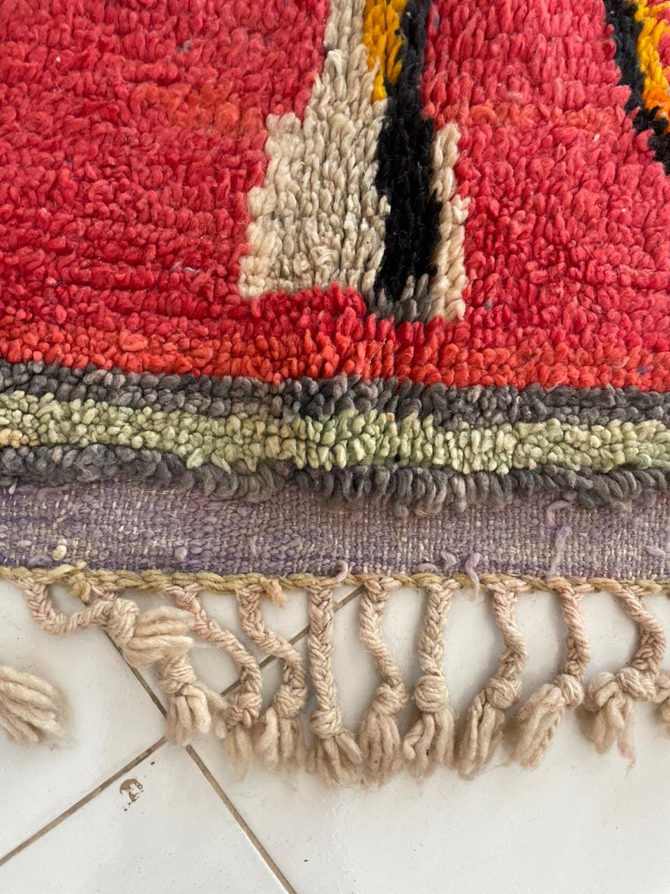 Detail view of the colorful Moroccan rug showcasing fringe edges and a vintage style.