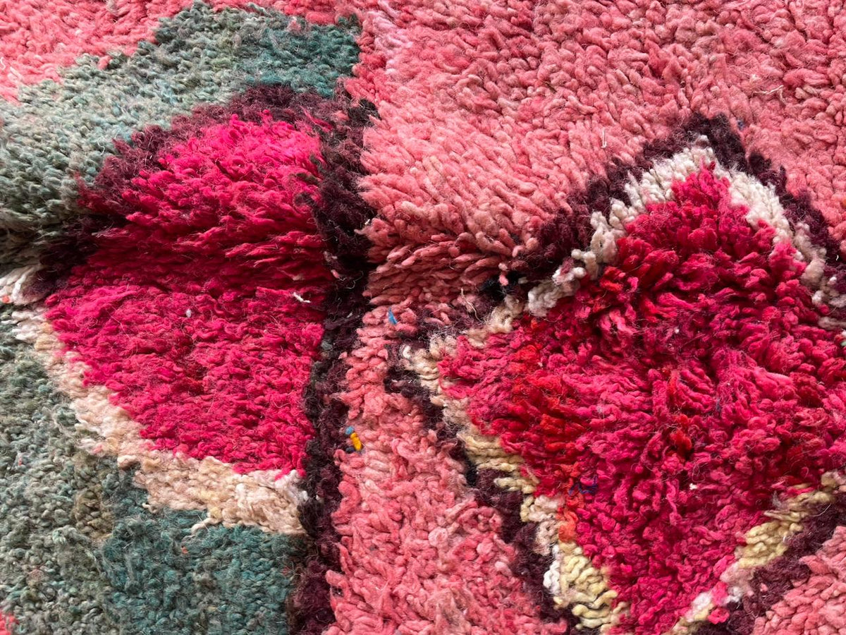 Close-up detail of the diamond shapes and soft texture on the red and pink Boujaad Moroccan rug.
