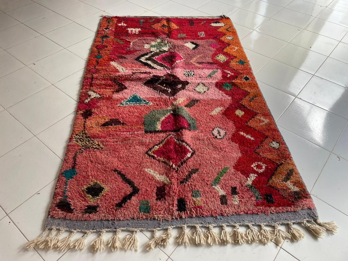 Close-up detail of the intricate designs on the red and pink Boujaad Moroccan rug against a white background.