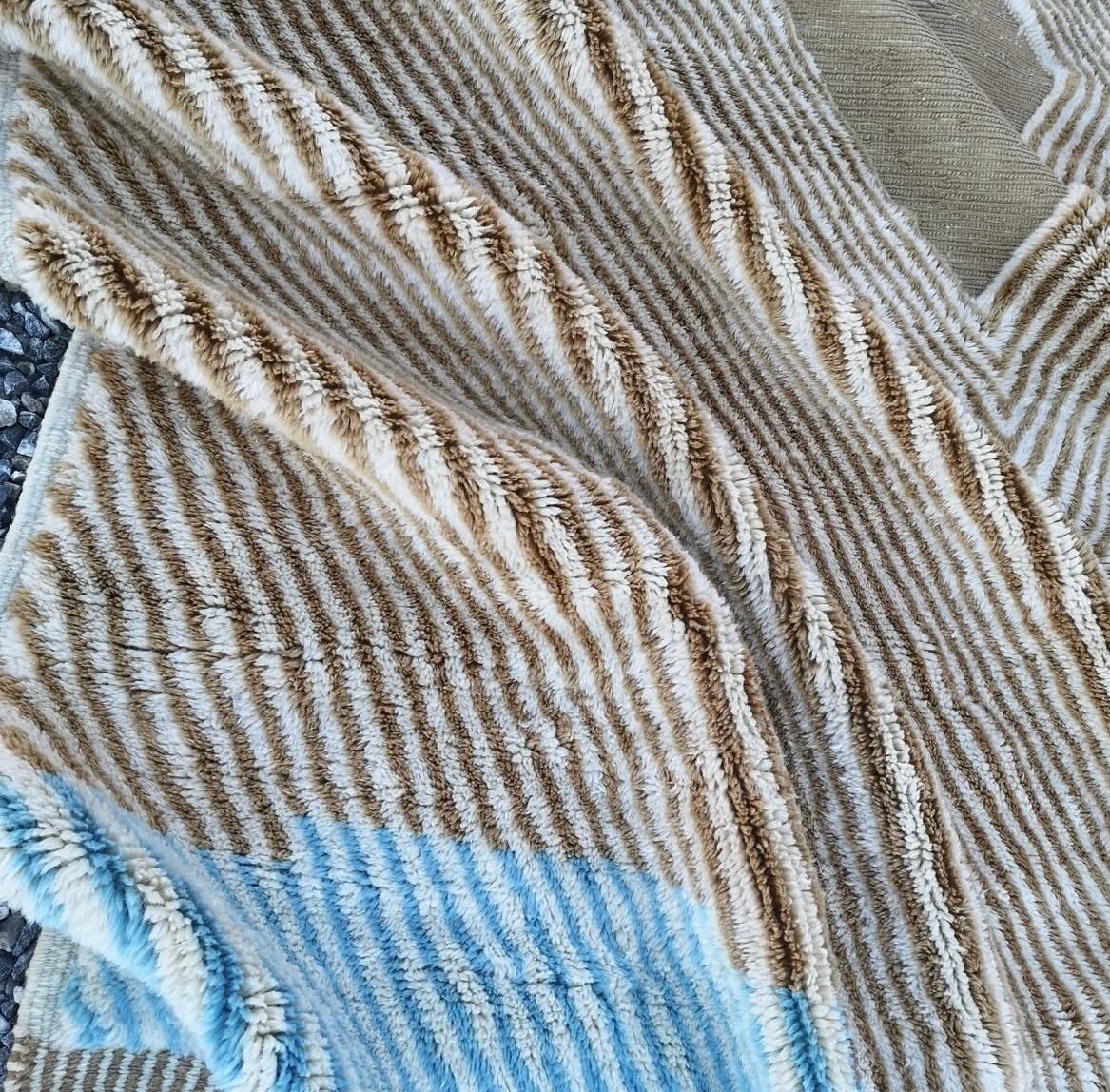 Close-up detail of a woven rug fabric featuring a striped pattern in beige and blue.