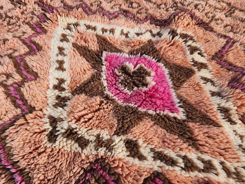 Close-up detail of the intricate pattern on a rust orange Moroccan rug with a soft texture.