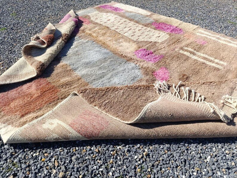 Flat view of a large beige and pink abstract Moroccan rug highlighting its design.