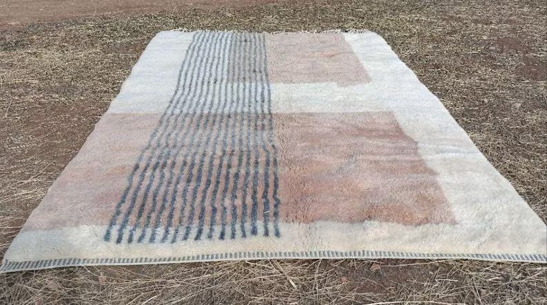 Lifestyle shot of a large Moroccan rug with a textured surface in beige and gray tones.