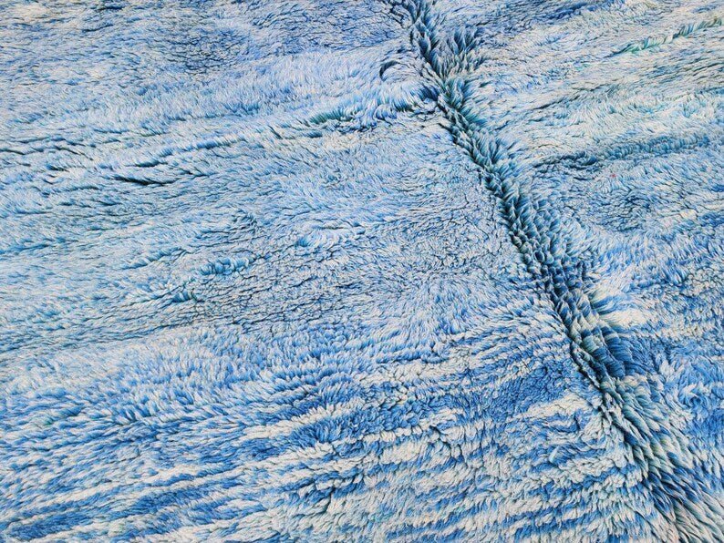 Close-up detail of the blue rug's textured surface and woven pattern.