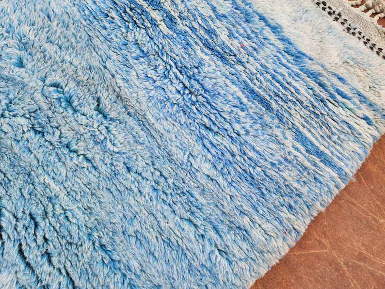 Close-up of the blue rug's textured fibers highlighting color variation.