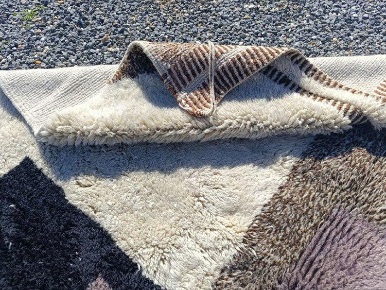 Close-up of the rolled edge of a beige and brown Moroccan rug.