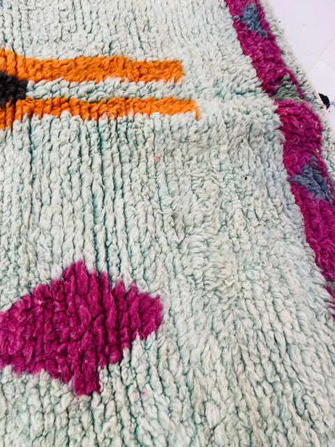 Detailed view of the colorful fibers on the blue and red abstract Moroccan rug.