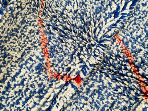 Close-up detail of the texture and abstract pattern of the blue and red Beni Ourain Moroccan rug.