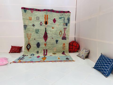 Lifestyle shot of the blue and red abstract Beni Ourain Moroccan rug on a white background.
