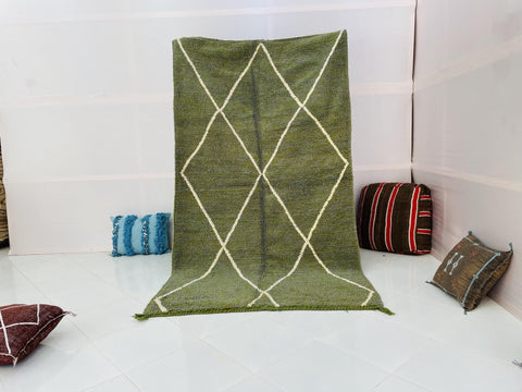 Lifestyle shot of a green and grey abstract design rug on a white background.