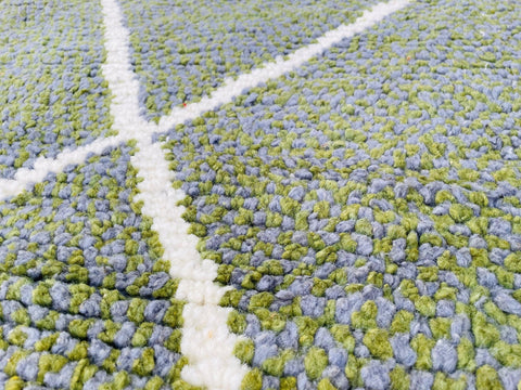 Close-up detail of the textured surface and abstract pattern of the green grey rug.