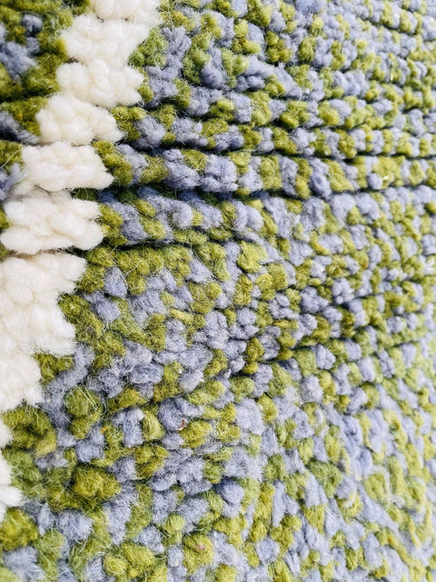 Close-up detail of the green grey rug highlighting its abstract pattern.