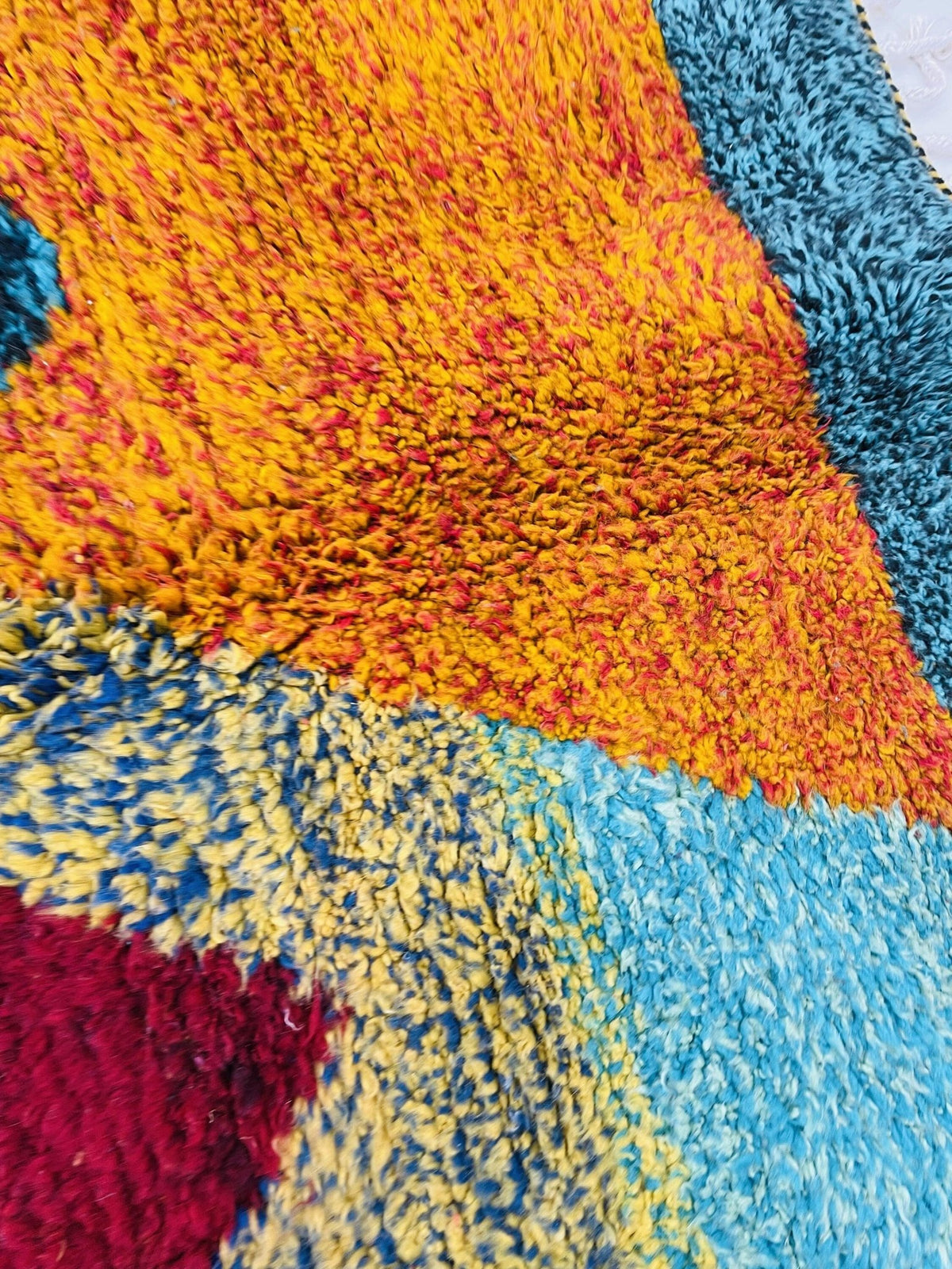 Close-up detail of an orange Moroccan rug showcasing colorful patterns in a studio environment.