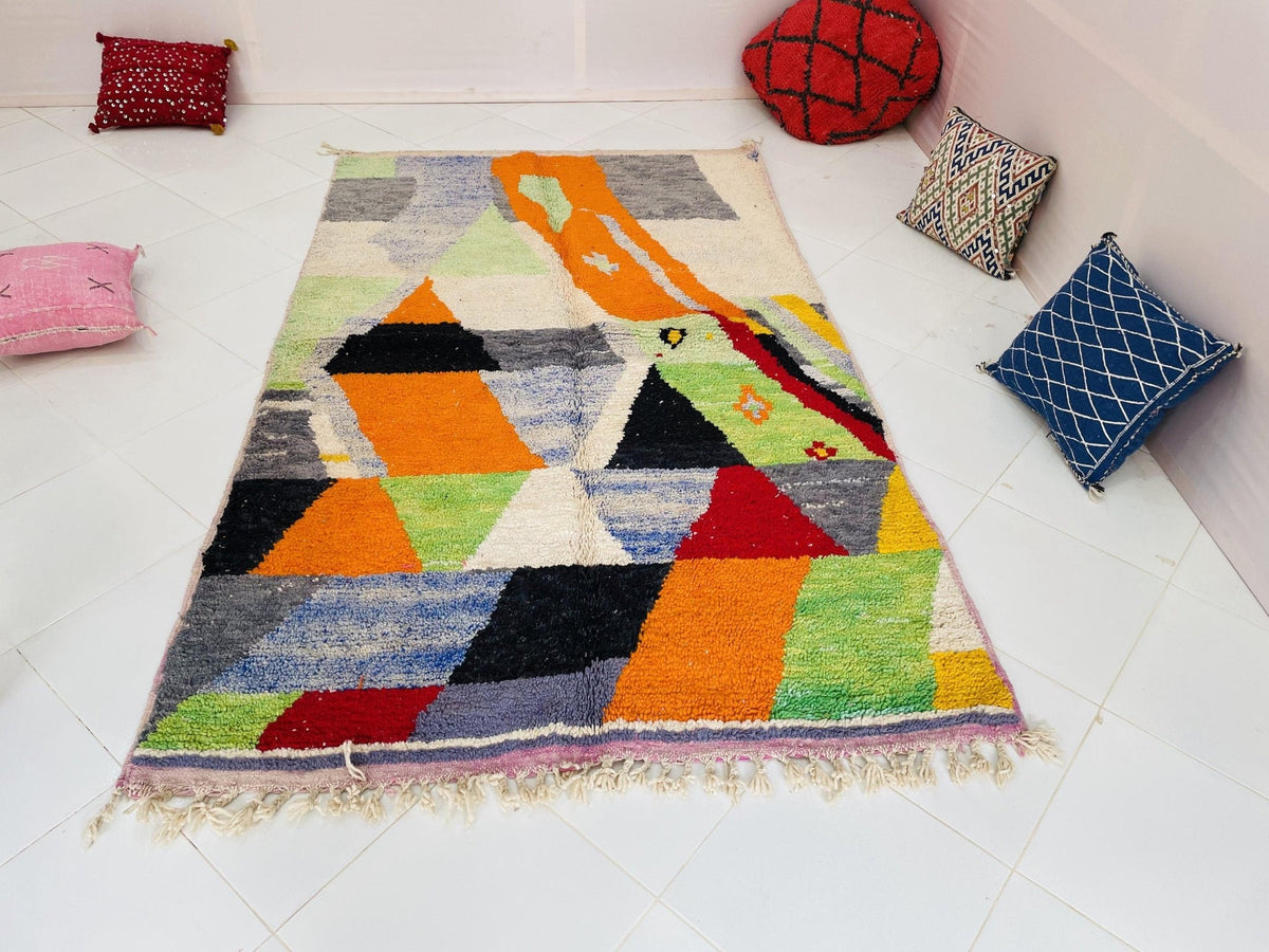 Lifestyle view of a colorful Moroccan rug featuring geometric designs in orange and green.