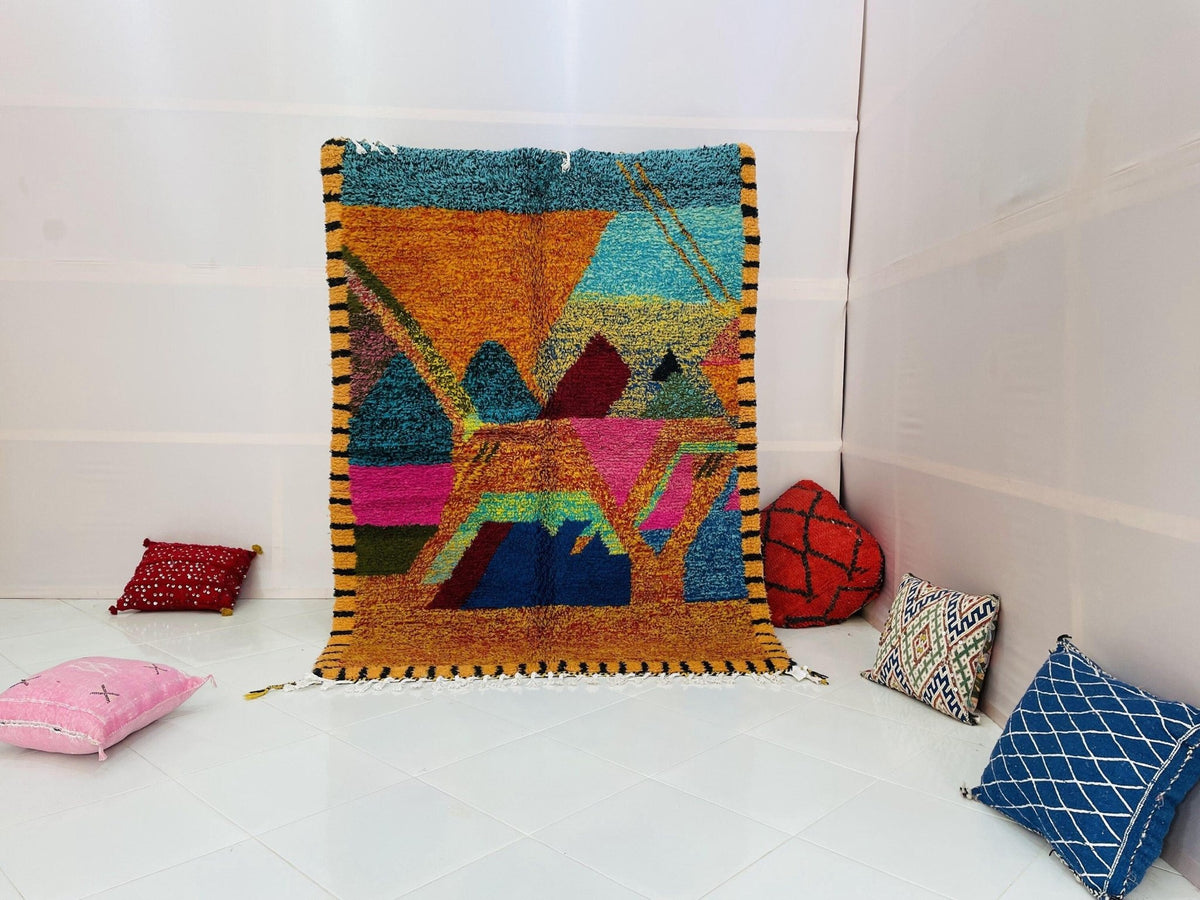Lifestyle shot of an orange abstract Moroccan rug with geometric patterns in a studio setting.