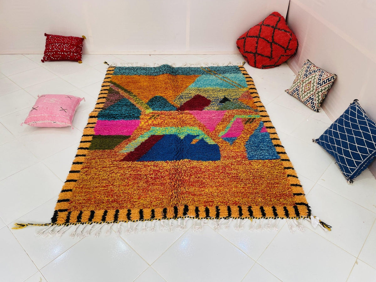 Lifestyle view of an orange Moroccan rug featuring geometric designs against a studio backdrop.