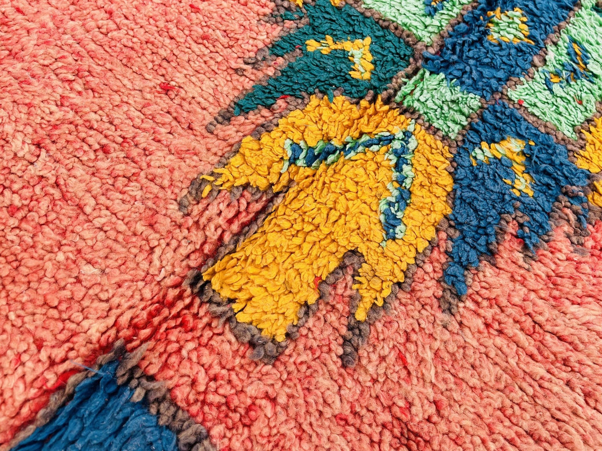 Detail shot of an orange Moroccan rug highlighting its geometric patterns and textured surface.