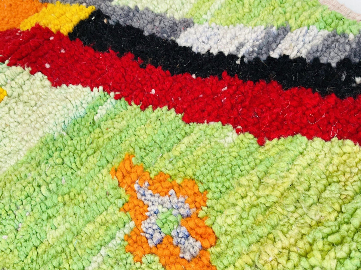 Close-up of a vibrant Moroccan rug featuring an abstract design with orange and green hues.