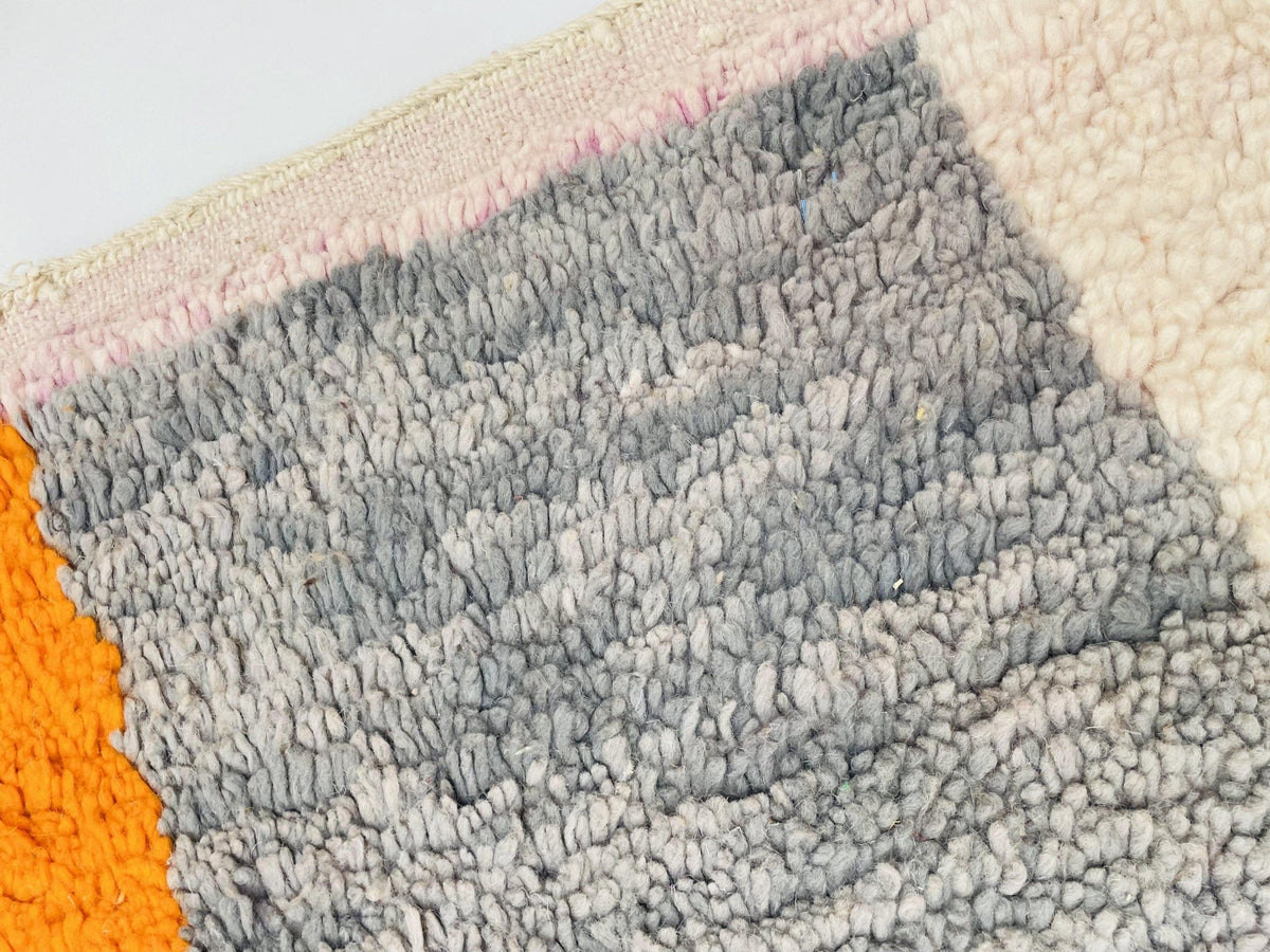 Close-up of a layered design on an orange Moroccan rug with white and gray accents.