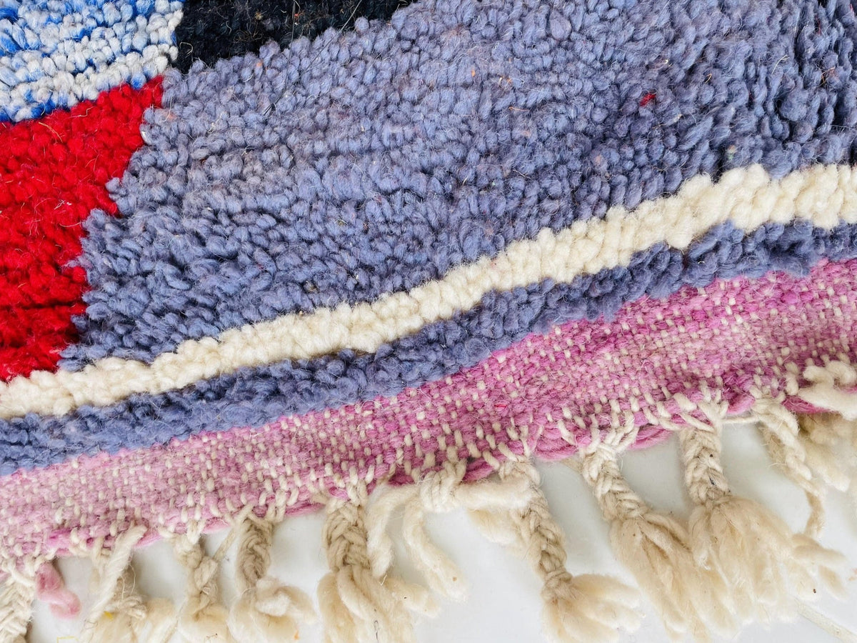 Close-up detail of the textured fibers of an orange Moroccan rug with colorful accents.