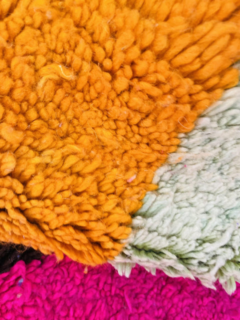 Lifestyle angle showcasing a colorful orange and blue abstract Moroccan rug on a white backdrop.