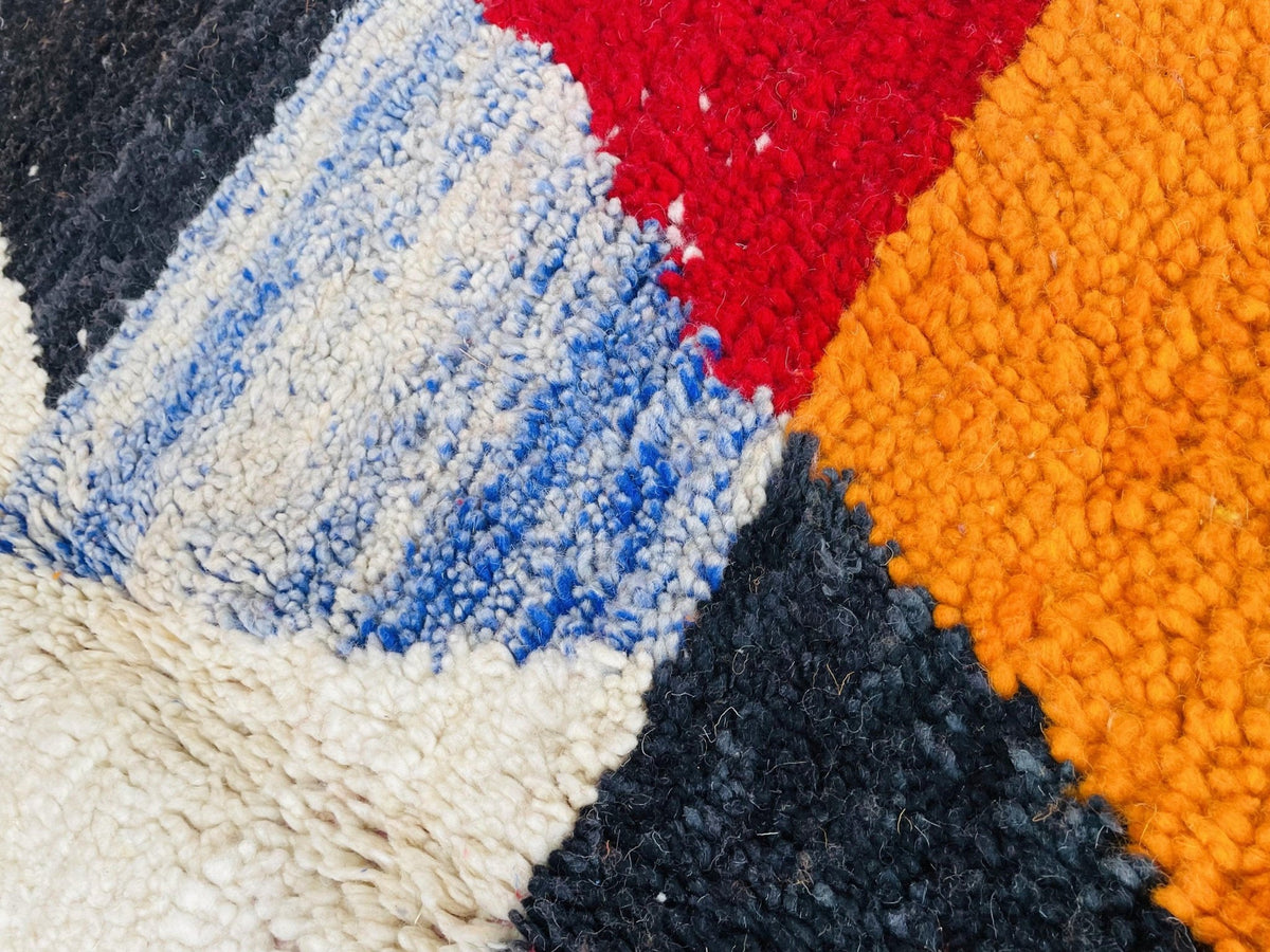 Detail shot of a colorful Moroccan rug displaying geometric patterns in orange and red.