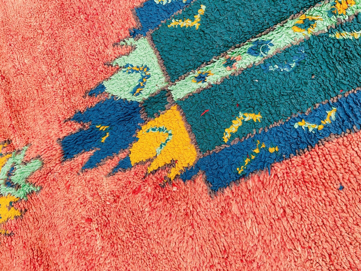 Detail shot of an orange Moroccan rug featuring geometric patterns and a textured surface.