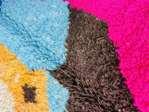 Detail shot highlighting the vibrant colors and textured surface of an orange and blue Moroccan rug.