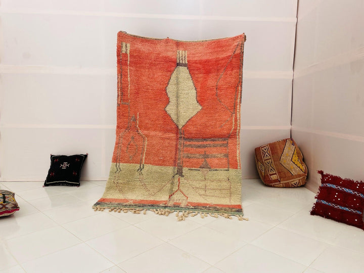 Lifestyle shot of the orange geometric Beni Ourain Moroccan rug on a white background.