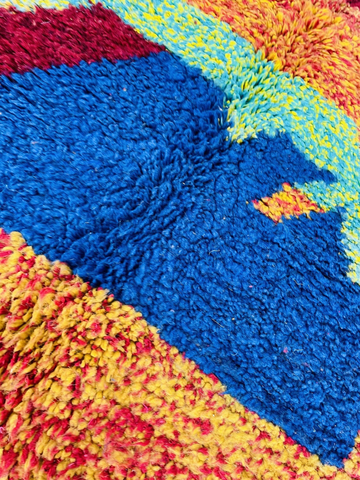 Detail view of a colorful Moroccan rug featuring orange and blue tones in a close-up shot.