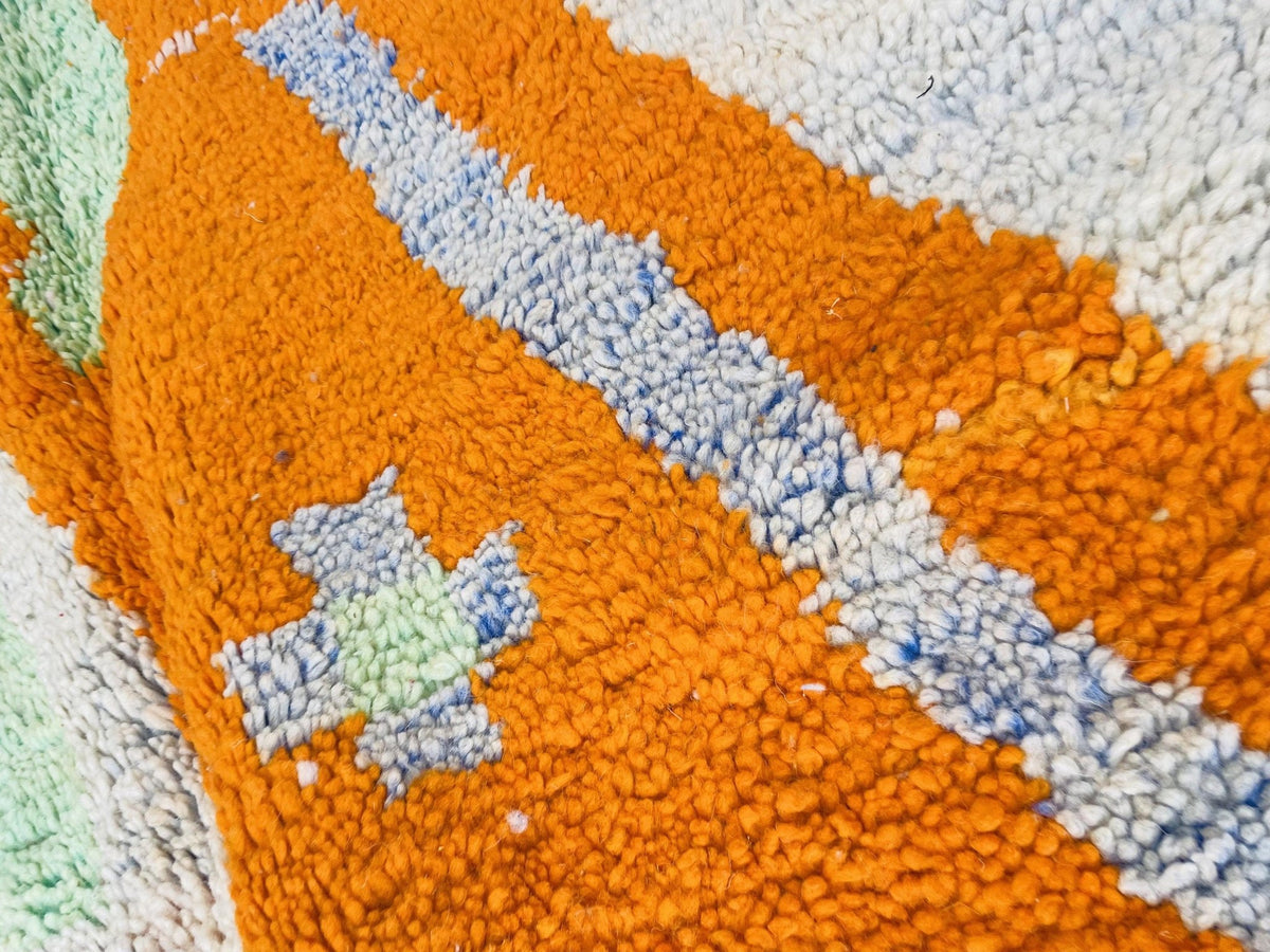 Detail view of a colorful Moroccan rug with a striped pattern in orange and blue.