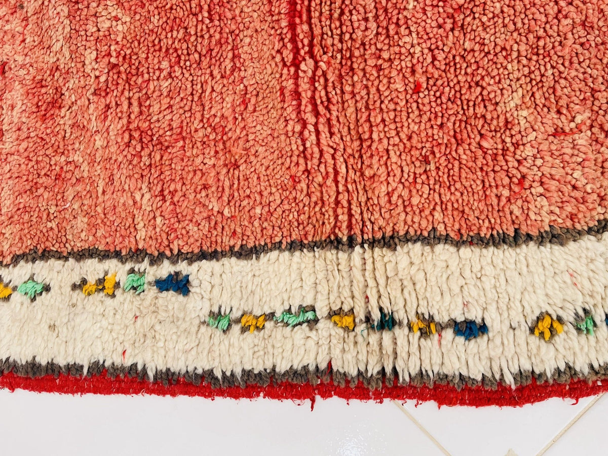 Close-up view of an orange Moroccan rug featuring geometric designs and a textured surface.