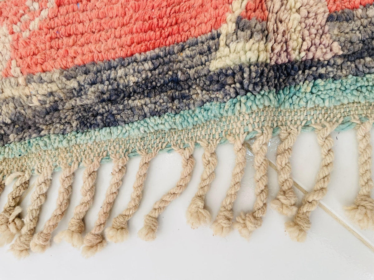 Close-up detail of the fringed edges of the orange geometric Beni Ourain Moroccan rug.