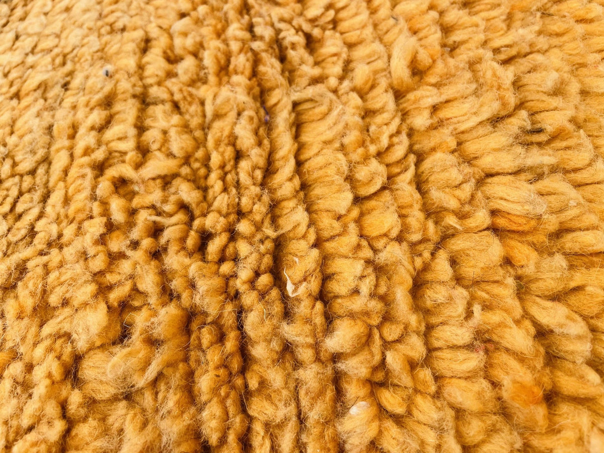 Close-up detail of a yellow wool rug highlighting its textured surface.