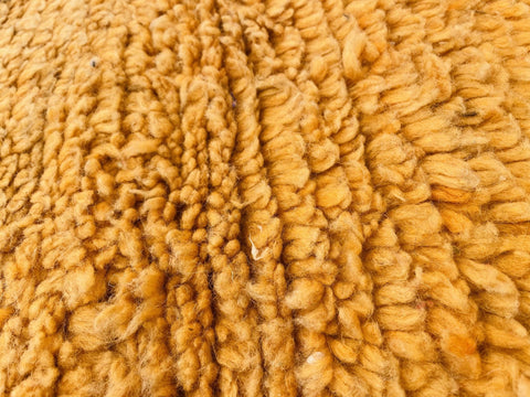 Close-up detail of a yellow wool rug highlighting its textured surface.