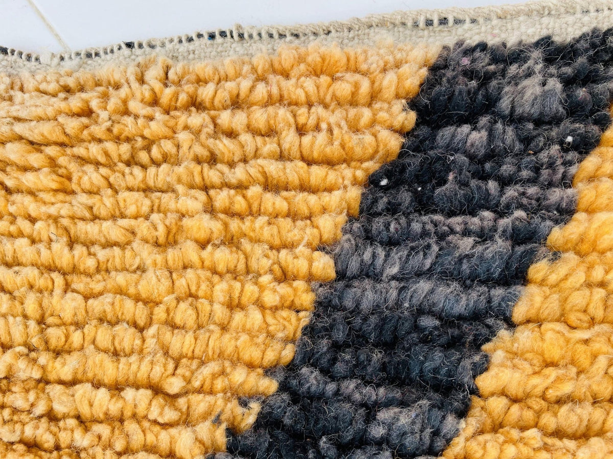 Close-up detail of a yellow and black Moroccan rug featuring a textured pattern.