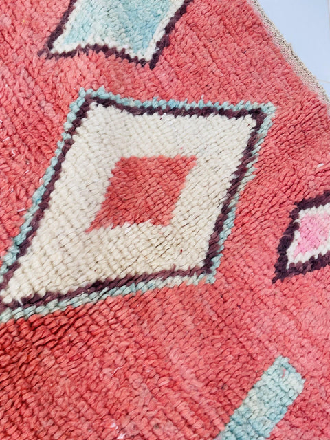 Close-up detail of a red and blue Moroccan rug featuring geometric patterns and textured wool.