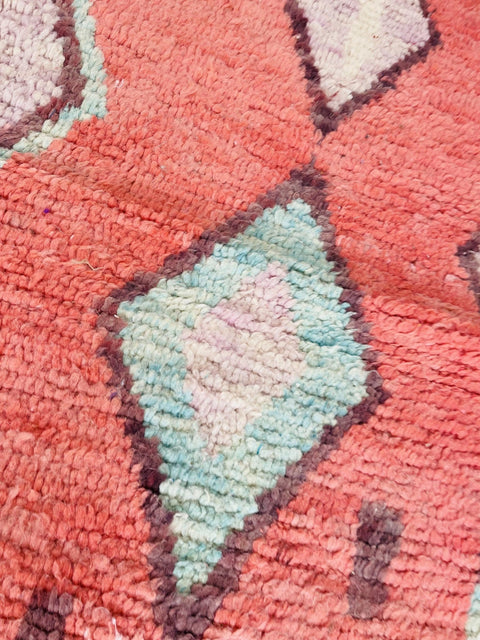 Close-up view of a red and blue Moroccan rug displaying geometric patterns and textured surface.