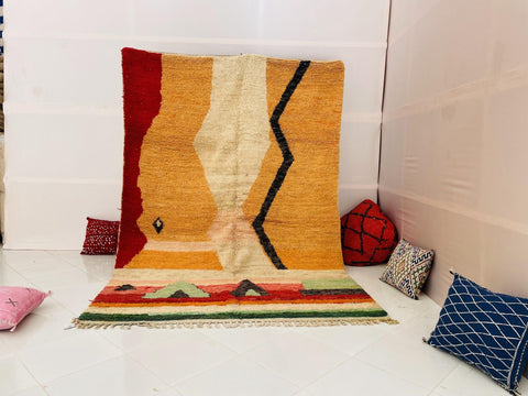 Lifestyle shot of a yellow Moroccan rug with geometric patterns in a studio setting.