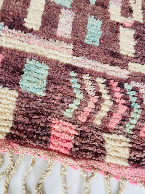 Close-up detail of a pink and blue Moroccan rug showcasing its intricate design and texture.