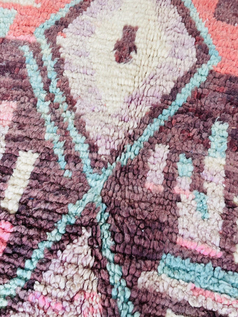Close-up detail of a cream and blue Moroccan rug highlighting geometric patterns and texture.